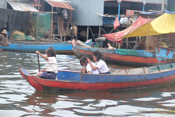 Vêtus de la chemise blanche traditionnelle, les enfants rejoignent l'école en barque.